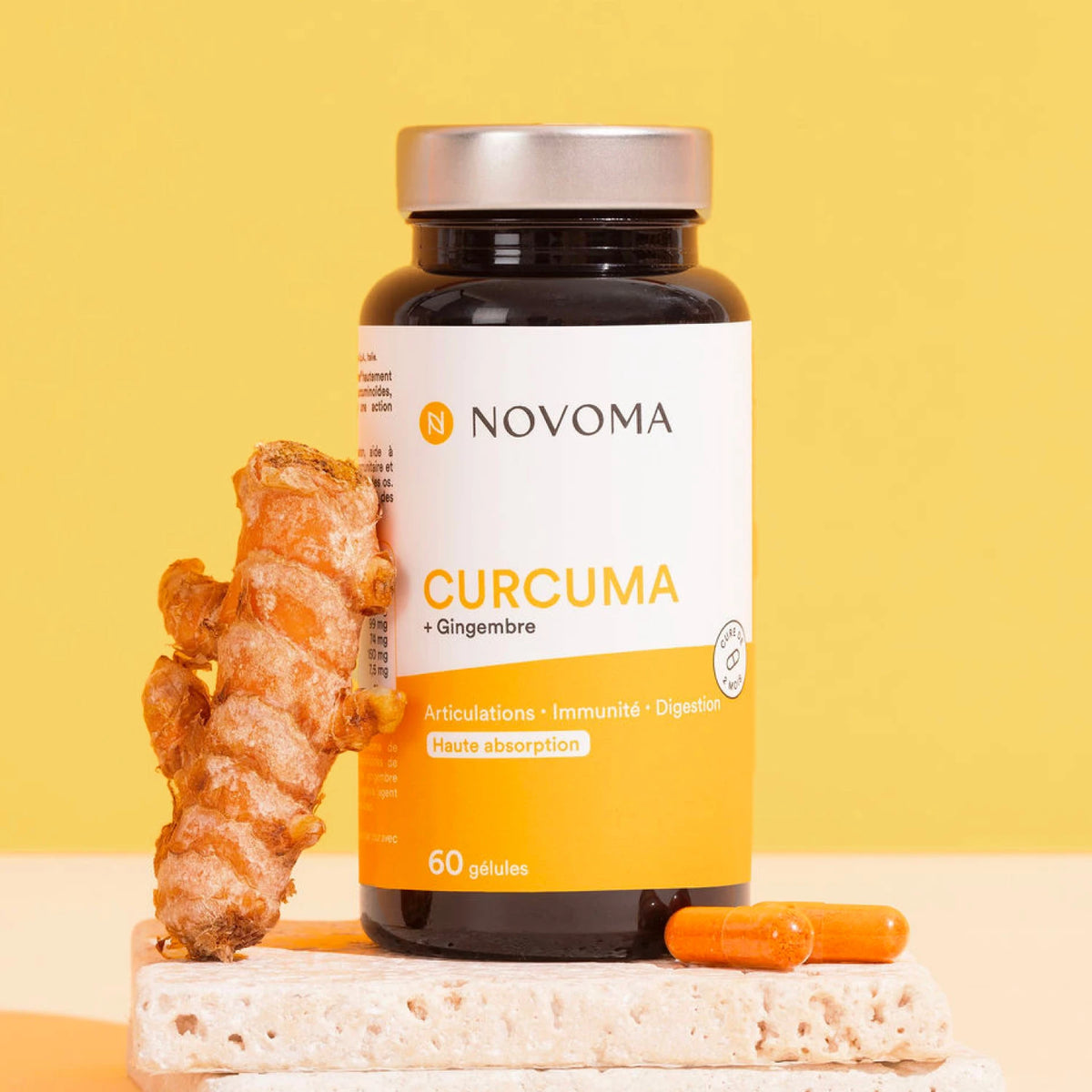 Pilulier de Curcuma Novoma posé près de racines de curcuma frais sur fond jaune