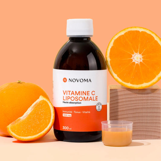 Flacon de Vitamine C liposomale liquide Novoma avec des oranges sur fond pêche