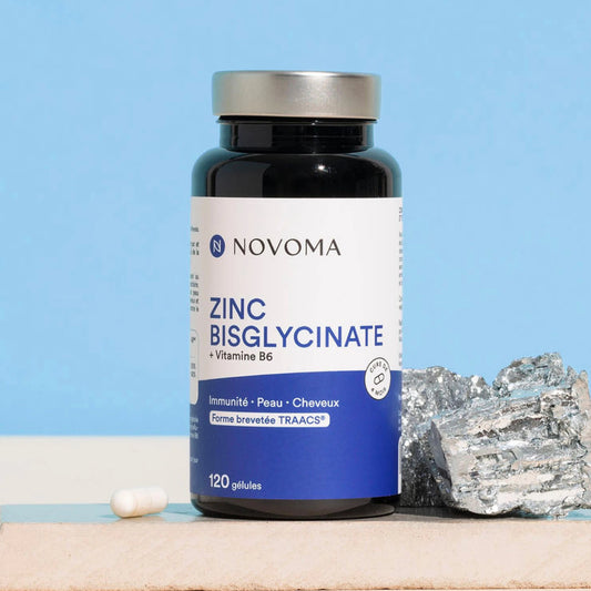 Pilulier de Zinc Bisglycinate Novoma près d'une roche minérale sur fond bleu