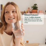 Femme souriante buvant un verre : 1 cuillère doseuse rase de L-Glutamine dans 200 ml d'eau