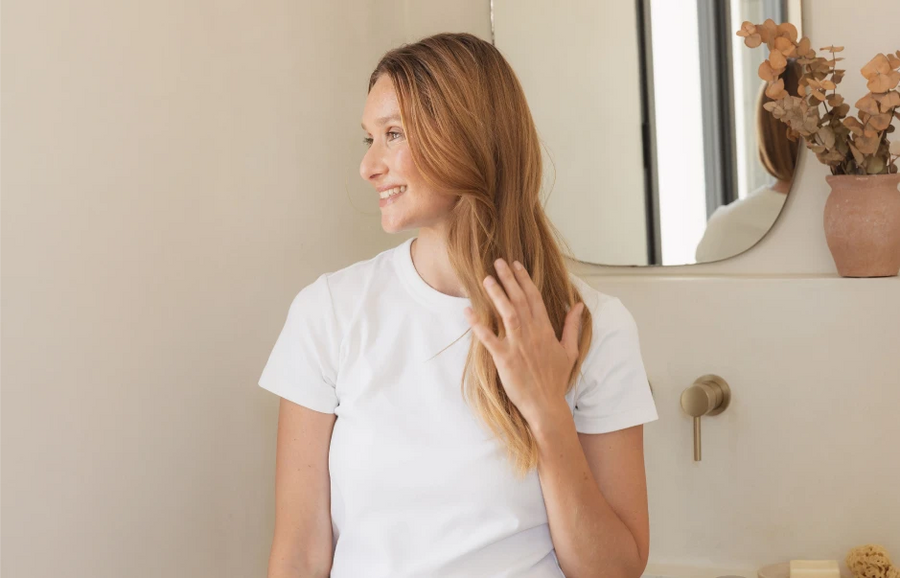 Femme qui se touche les cheveux dans une salle de bain