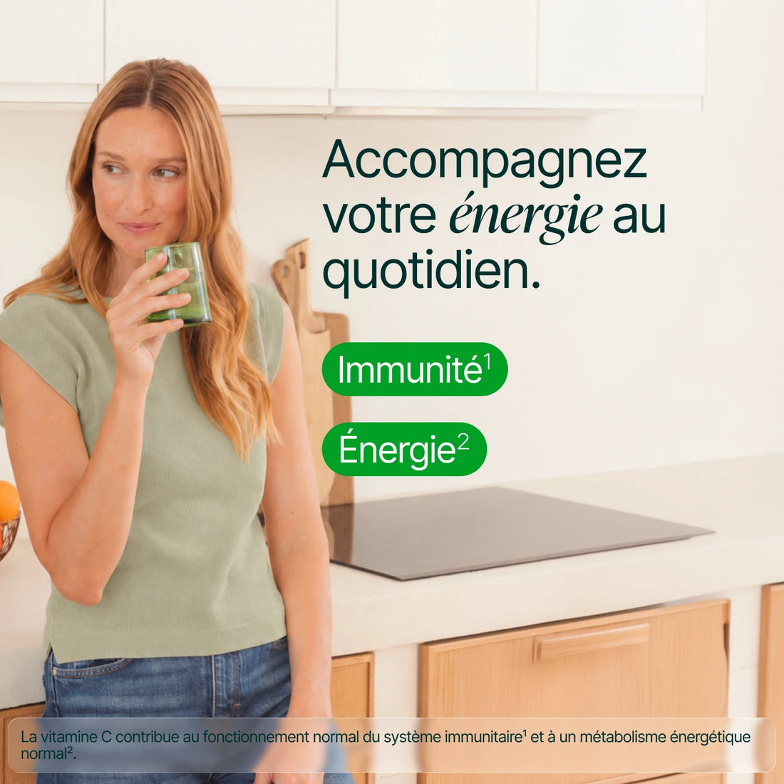 Femme dans sa cuisine, un verre à la main : accompagnez votre énergie au quotidien, immunité et énergie
