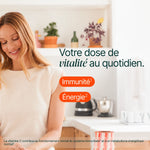 Femme dans sa cuisine, un verre à la main : votre dose de vitalité au quotidien, immunité et énergie