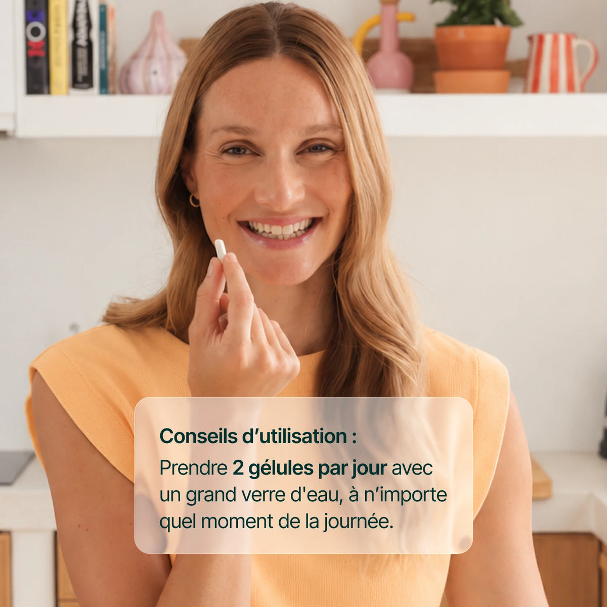 Femme souriante tenant une gélule de vitamine D3 : 2 gélules par jour avec un grand verre d'eau